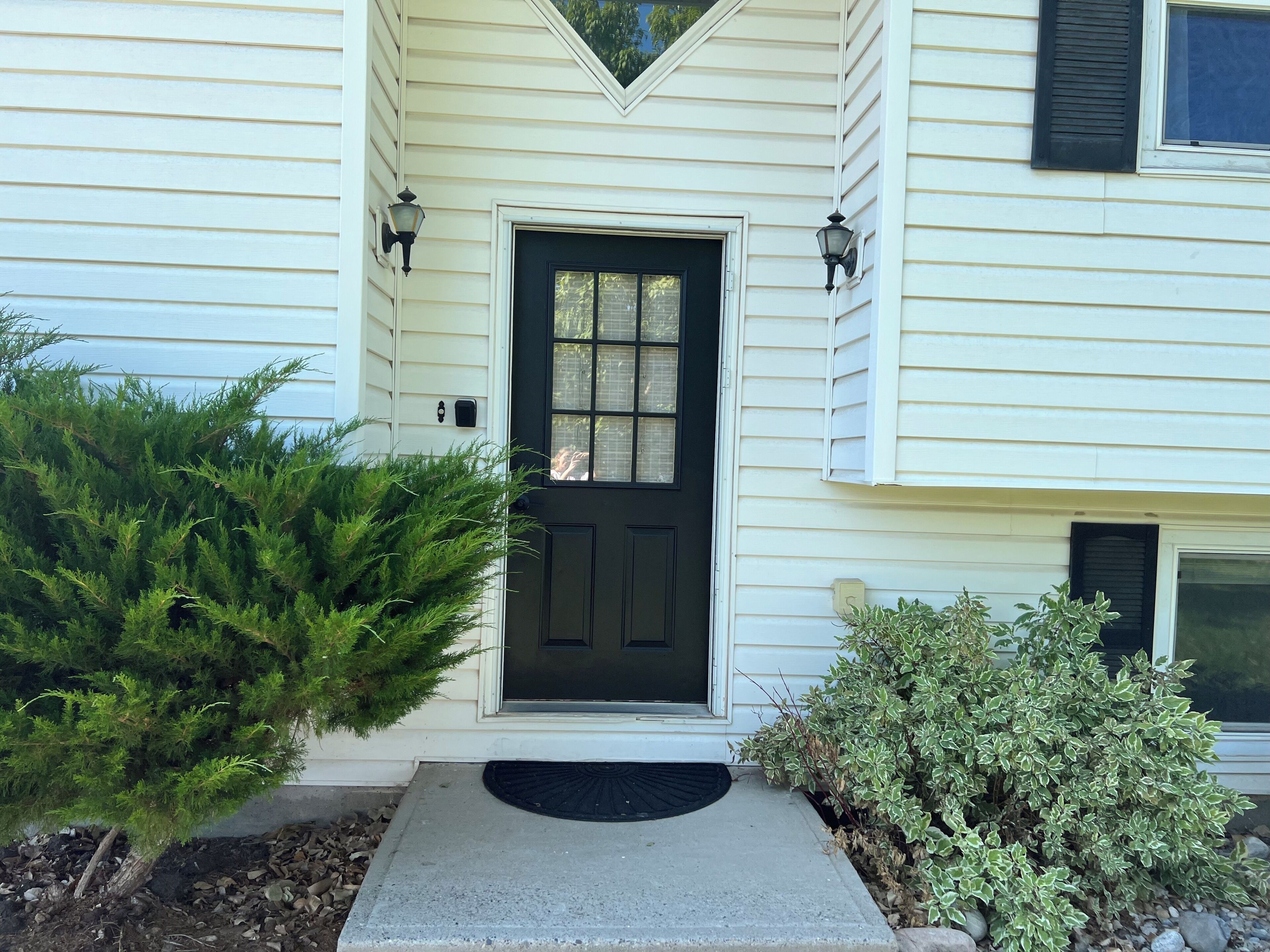 A house with a black front door, two wall-mounted lights, and a small step leading to the entrance.