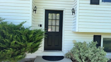 A house with a black front door, two wall-mounted lights, and a small step leading to the entrance.