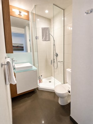 A modern bathroom with a glass-enclosed shower, a white sink, and a toilet. - StayToronto - The Atmos Suites (Toronto)