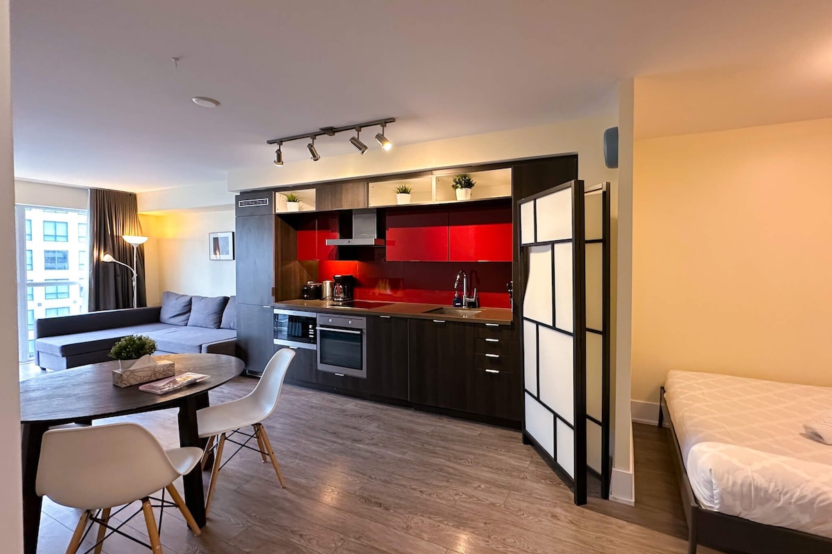 A modern apartment with a kitchen, dining area, and a bed.