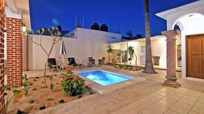 A courtyard with a swimming pool, outdoor seating, and a building with a white facade. - Single-story house with a private pool, within walking distance of the beach (La paz)
