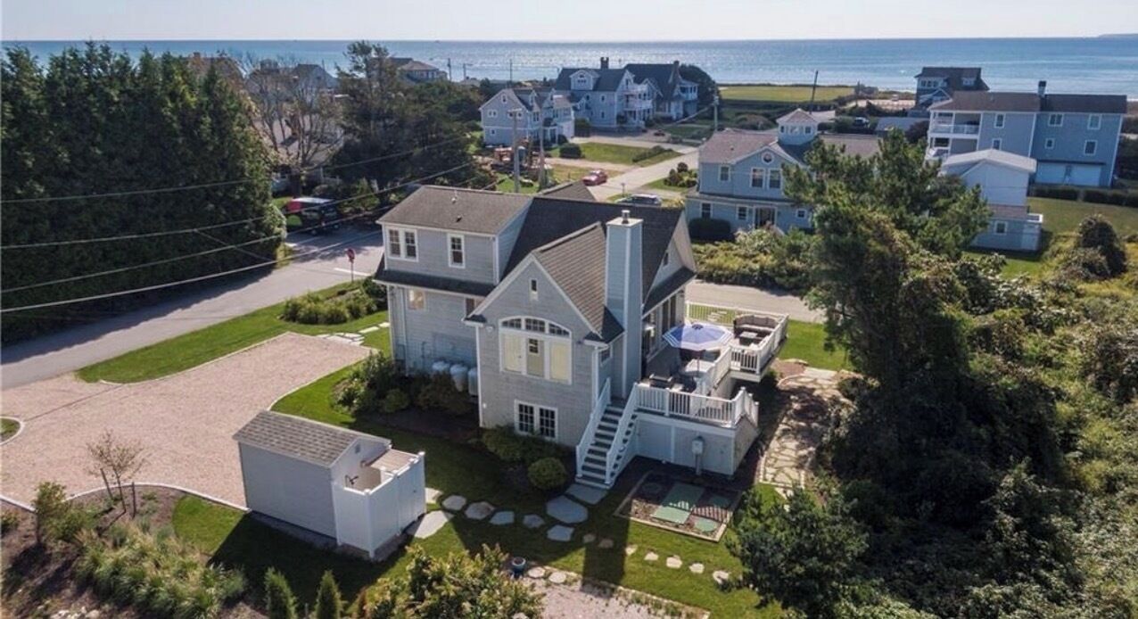 A two-story house with a front porch, a driveway, and a small garden area.