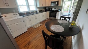 Una cocina con armarios blancos, microondas, horno y una mesa de comedor con posavasos.