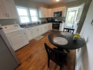 A kitchen with white cabinets, a microwave, an oven, and a dining table with placemats. - Vintage Charm Near Pilot Mountain and Mount Airy (Westfield)