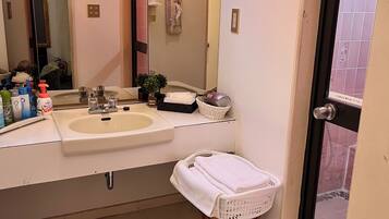 A bathroom with a sink, mirror, towel rack, and a small stool.