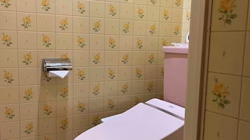 Un baño con inodoro, secamanos y pared con un estampado de flores.