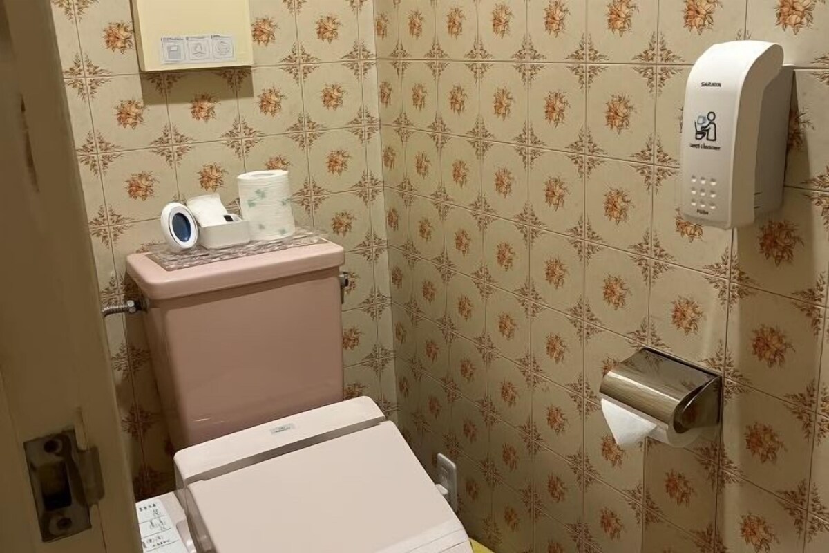 Un baño con inodoro, dispensador de toallas de papel y secador de manos.