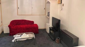 A room with a red sofa, a television, a white wardrobe, and a small table with a tissue box. - Hotel Robin (Yachimata)