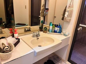 Un baño con lavamanos, espejo y distintos artículos de aseo.