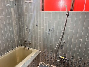 A bathroom with a bathtub, a shower, and tiled walls.