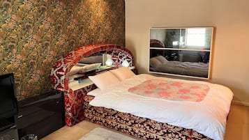 Un dormitorio con cama, espejo, cómoda y televisor.