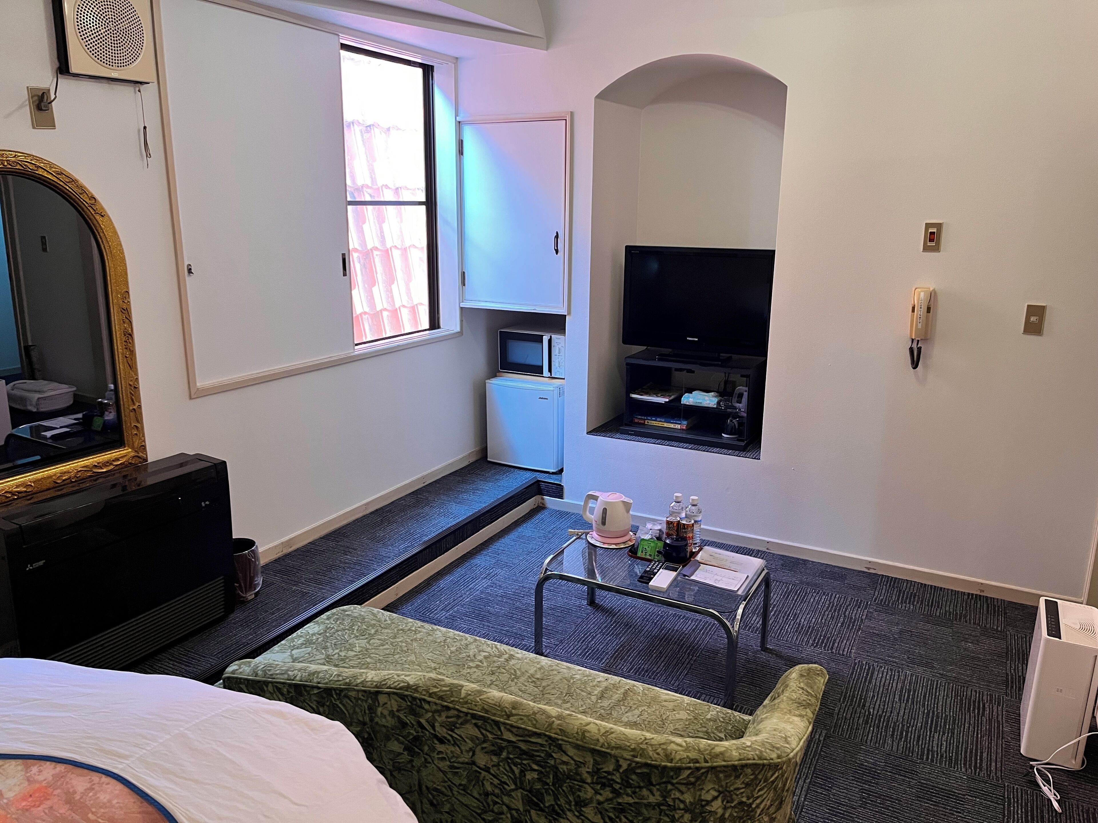 A hotel room with a bed, a television, a small kitchenette, and a seating area with a table and chairs.