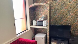 A compact living space with a red upholstered chair, a television, a refrigerator, and a microwave on a shelf. - Hotel Robin (Yachimata)