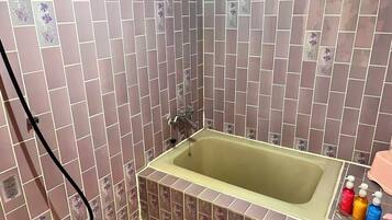 A bathroom with a bathtub, tiled walls, and a showerhead.