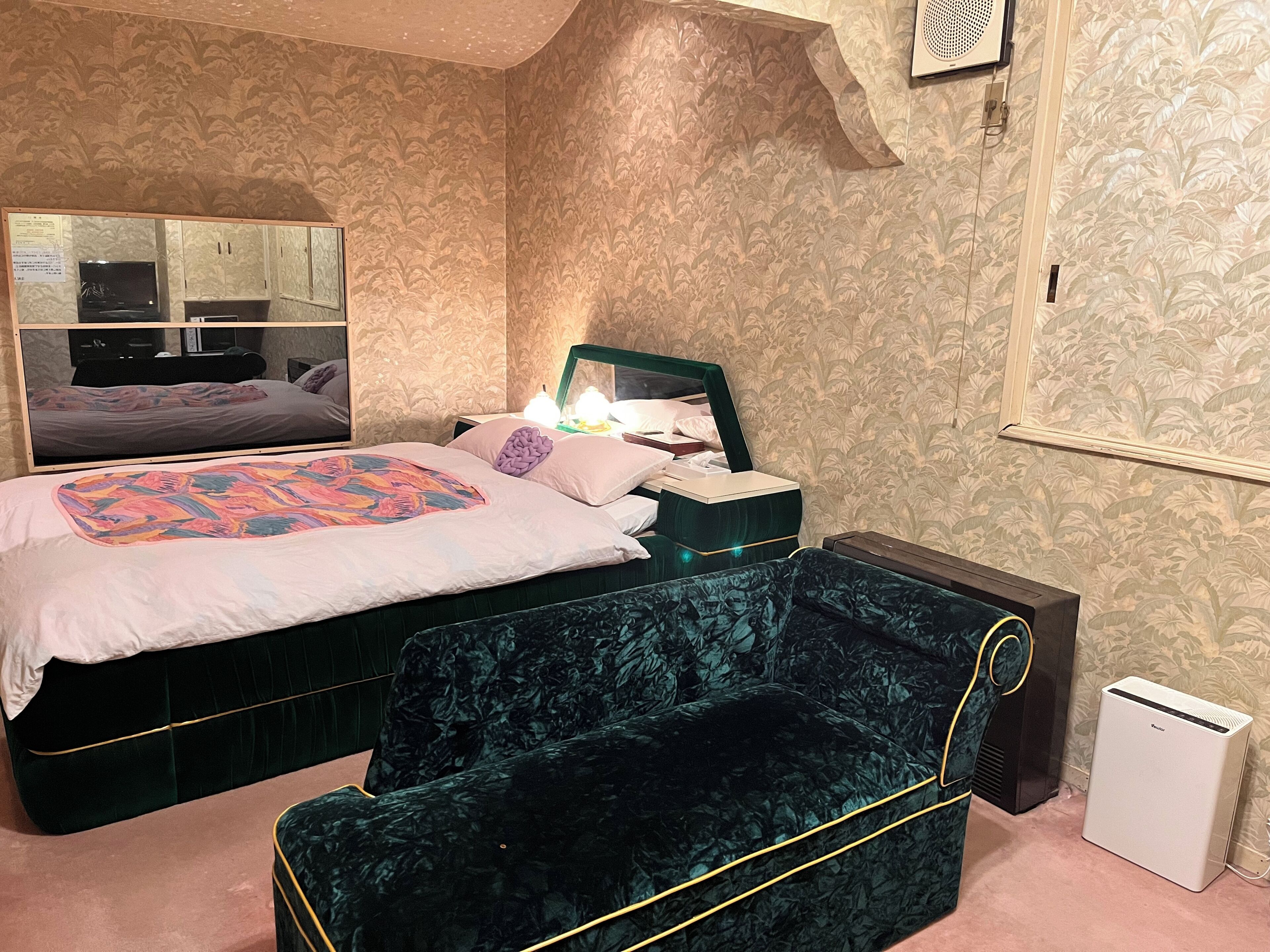 A bedroom with a bed, bedside table, lamp, and a mirror.