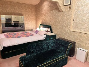 Un dormitorio con cama, mesita de noche, lámpara y espejo.