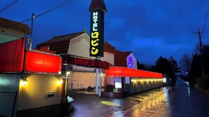 A hotel with a prominent sign, a covered entrance, and a red awning. - Hotel Robin (Yachimata)