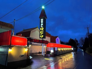 A hotel with a prominent sign, a covered entrance, and a red awning.