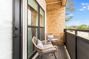 Ein Balkon mit zwei Korbstühlen und einer Holzwand.