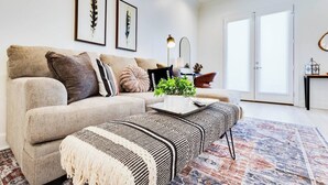 A modern living room with a sectional sofa, a coffee table, and a patterned rug. - 3 BD Designer Townhaus | River Ranch & Shopping (Lafayette)