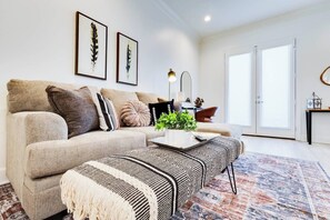 Ein modernes Wohnzimmer mit einem Ecksofa, einem Couchtisch und einem gemusterten Teppich.