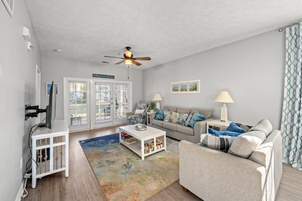 A living room with a white sofa, a coffee table, a TV, and a ceiling fan.