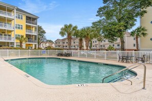 A swimming pool with a 3 FT depth marker, surrounded by a white fence, with apartment buildings in the background. - Ocean Keyes 3BR First Floor Condo - North Myrtle Beach (North Myrtle Beach)