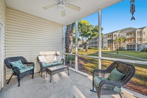 A covered porch with wicker furniture, a ceiling fan, and a view of a residential complex. - Ocean Keyes 3BR First Floor Condo - North Myrtle Beach (North Myrtle Beach)