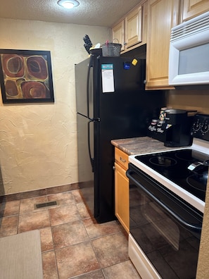 A compact kitchen with a refrigerator, coffee maker, and stove.
