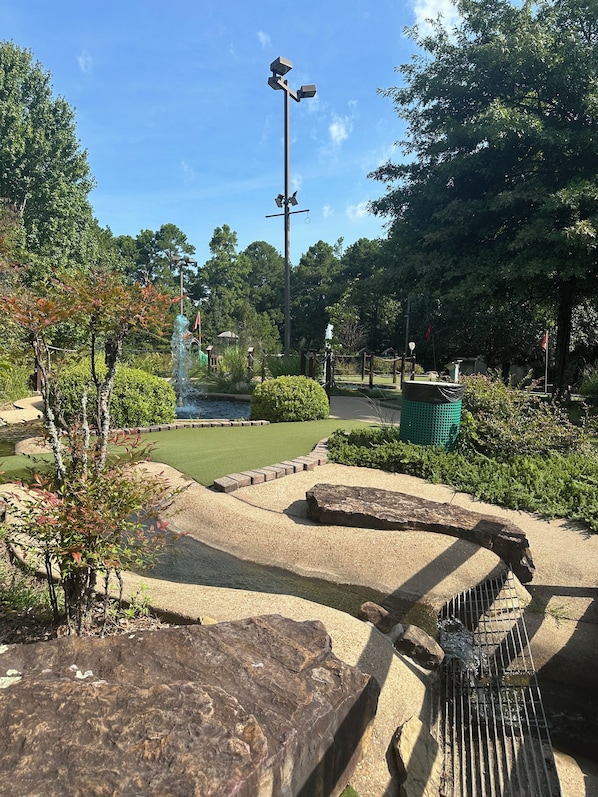 A landscaped garden with a pond, a pathway, and a street lamp.