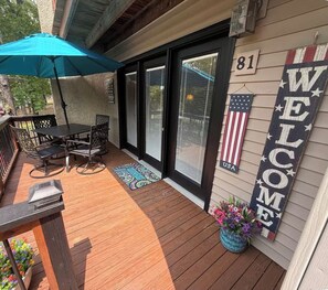 Una terraza de madera con una mesa, sillas, un cartel de bienvenida y una bandera estadounidense.