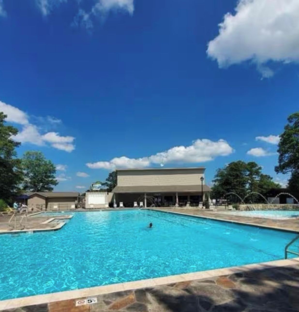 Una piscina con un cielo azul despejado y un edificio al fondo.