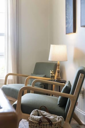 Ein Zimmer mit zwei Sesseln, einer Lampe und einer kleinen Statue auf einem Nachttisch.
