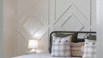 A bed with a headboard, a bedside lamp, and a patterned rug.