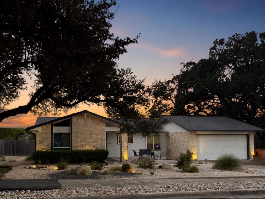 A two-story house with a garage, stone exterior, and a patio with outdoor seating.