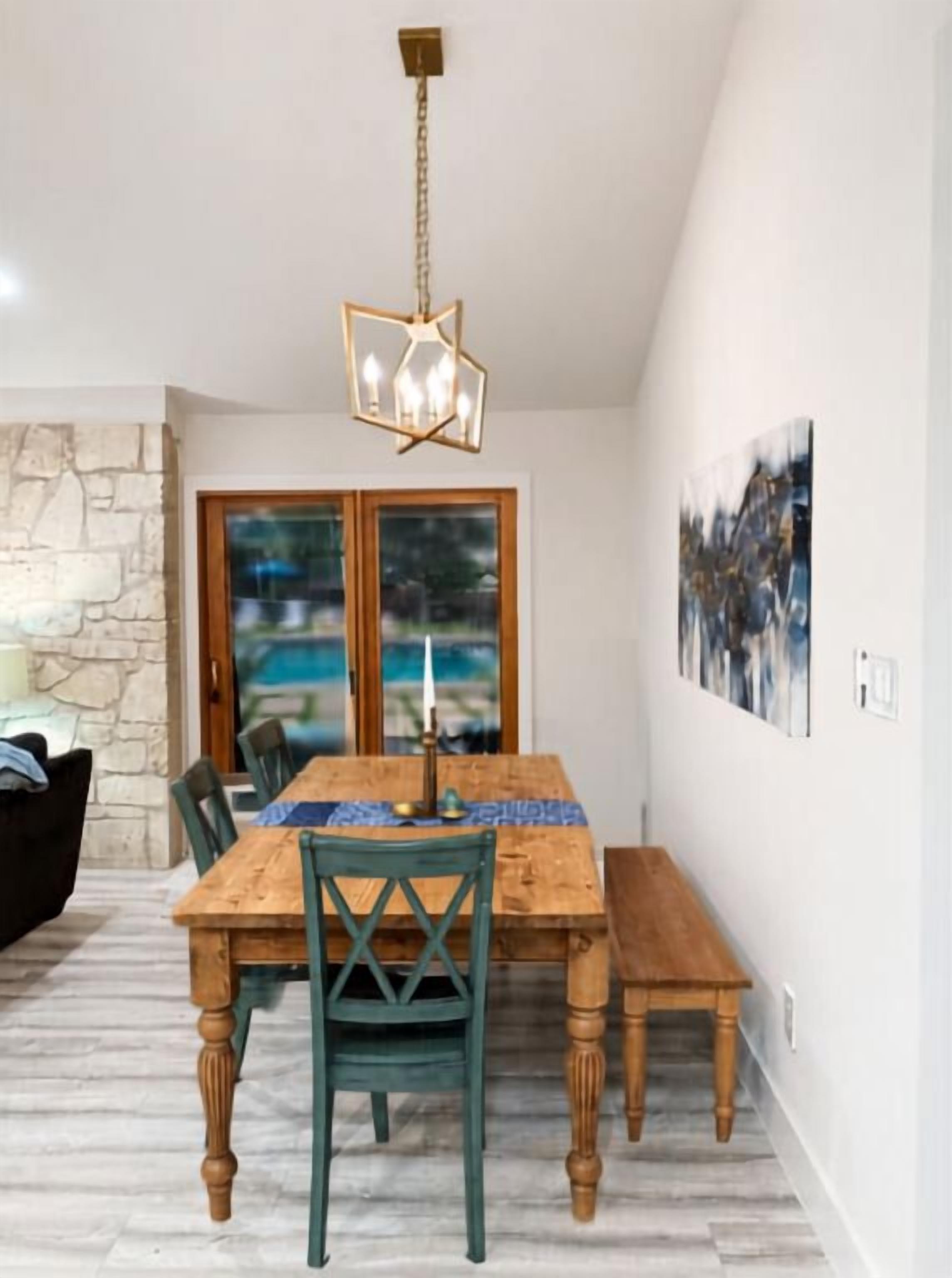 A dining area with a wooden table, chairs, and a hanging light fixture.