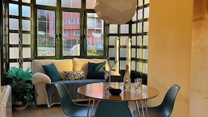 A cozy living area with a sofa, a round table, and chairs, a potted plant, and a view of a building outside. - Portosin, a beautiful home with spectacular views of the Muros-Noia estuary (Portosin)