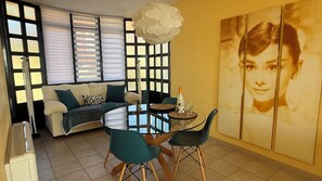 A dining area with a round glass table, two chairs, a sofa with cushions, a decorative light fixture, and a large framed artwork on the wall. - Portosin, a beautiful home with spectacular views of the Muros-Noia estuary (Portosin)