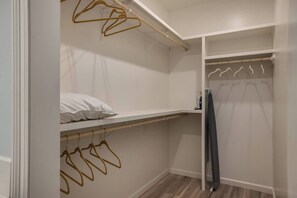 A walk-in closet with wooden hangers, a shelf with a pillow, and a hanging garment. - Freetown Farmhouse | Modern 3BR w/Big Kitchen (Lafayette)