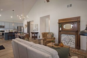 A modern living room with a fireplace, a dining area, and a kitchen in the background. - Freetown Farmhouse | Modern 3BR w/Big Kitchen (Lafayette)