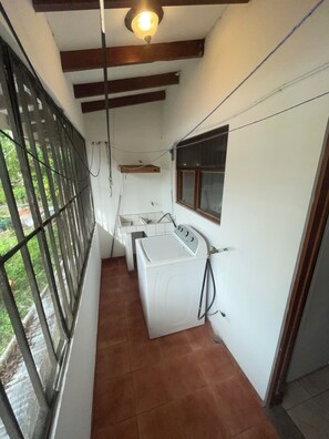 A laundry room with a washing machine, a drying rack, and a window.