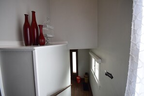 A hallway with a white door, a red bucket, and a jar on the floor. - Capitol Retreat (Salt Lake City)