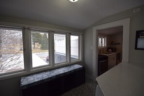 A room with a large window, a bench, a kitchen area, and a patterned floor. - Capitol Retreat (Salt Lake City)