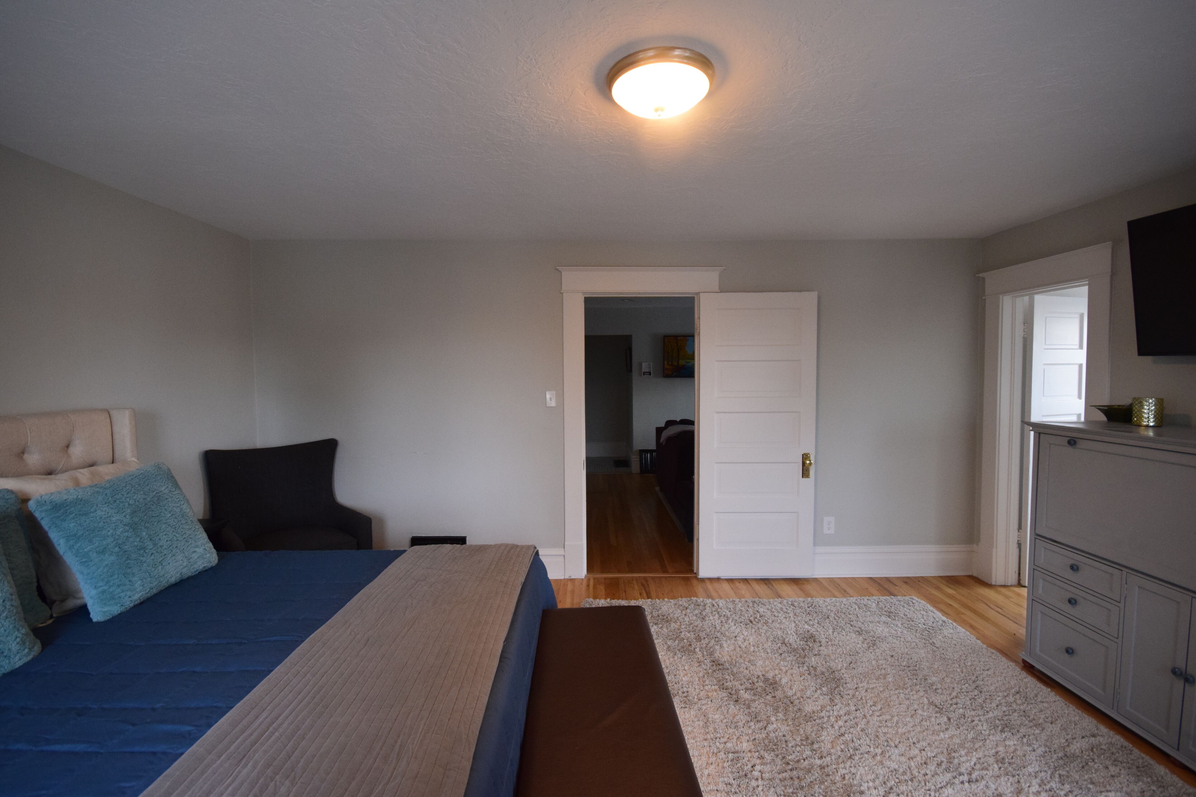 Un dormitorio con cama, cómoda y puerta que da a otra habitación.