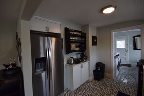 A modern kitchen with a stainless steel refrigerator, a coffee maker, and a microwave on the countertop. - Capitol Retreat (Salt Lake City)