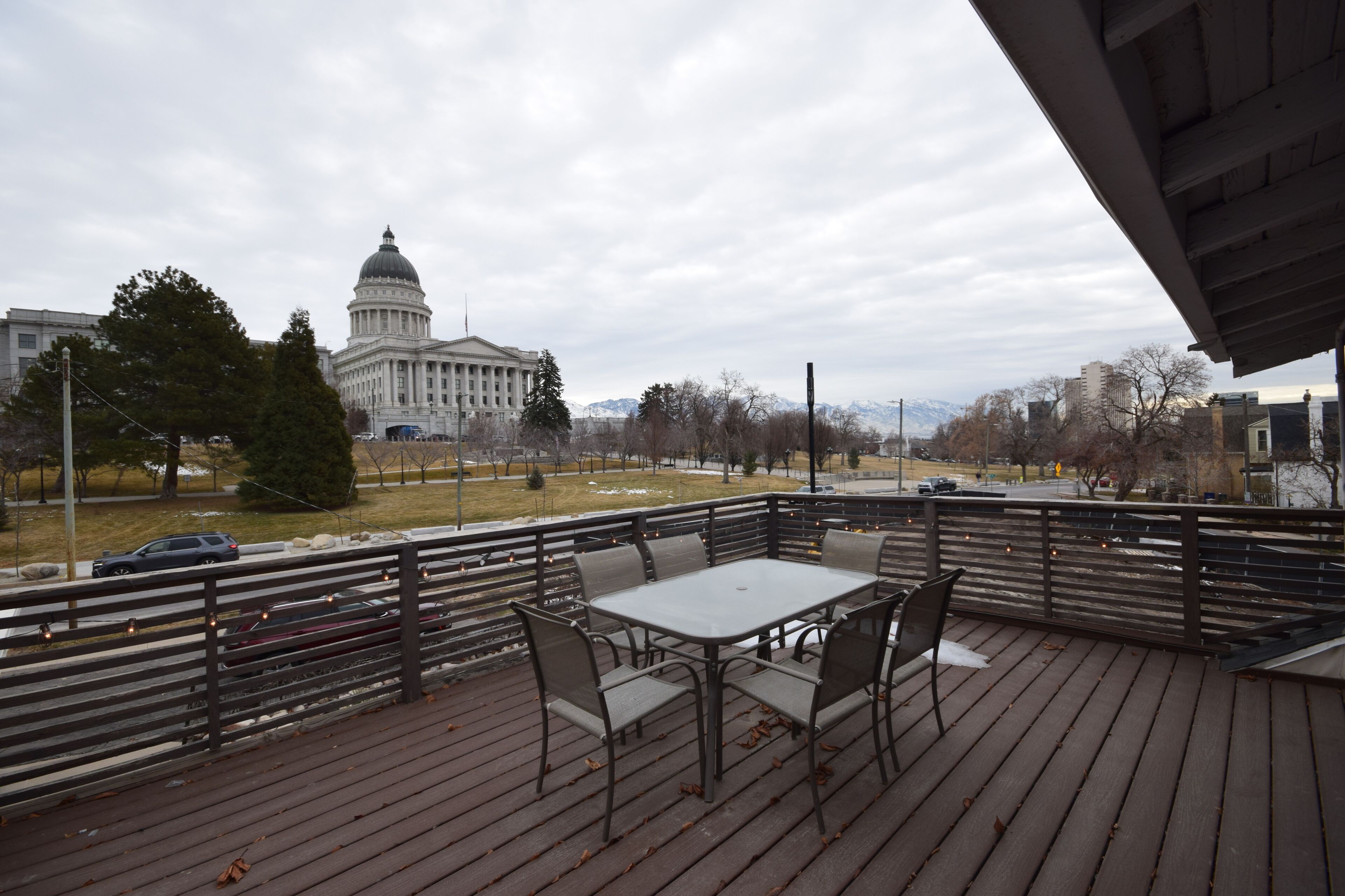 A deck with a table and chairs, overlooking a cityscape with a prominent government building.