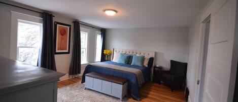 A bedroom with a bed, a bench, a dresser, and a chair.