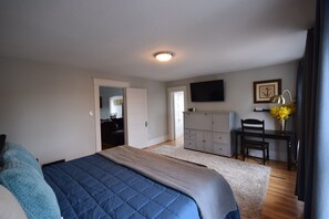 A bedroom with a bed, a desk, a chair, a television, and a door leading to another room. - Capitol Retreat (Salt Lake City)