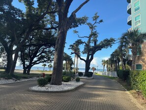 A paved walkway lined with trees and a building with balconies. - Welcome to "The Coastal Beach Villa"- Your Seaside Retreat in Gulfport, MS! (Gulfport)