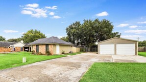 A residential property with a paved driveway, a garage, and a lawn. - NEW! Kid Friendly 3BR Fenced Yard - Sports Complex (Youngsville)